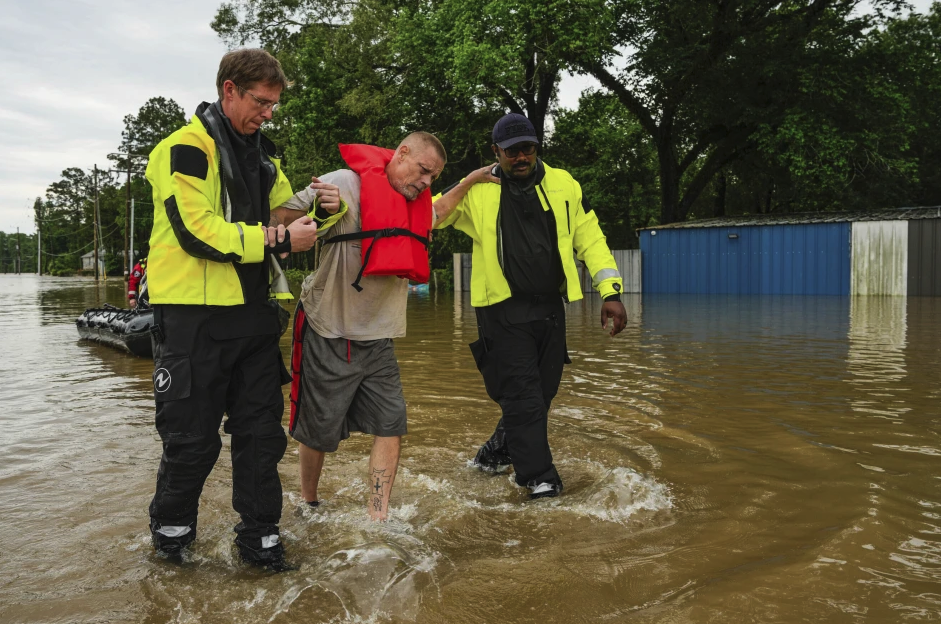 Tim McCanon, center, is rescued by the Community Fire Department during severe flooding on Friday, May 3, 2024, in New Caney, Texas