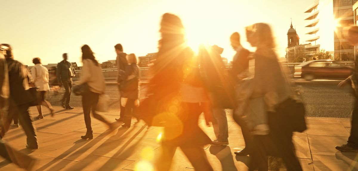 People walking in a city with a bright sun