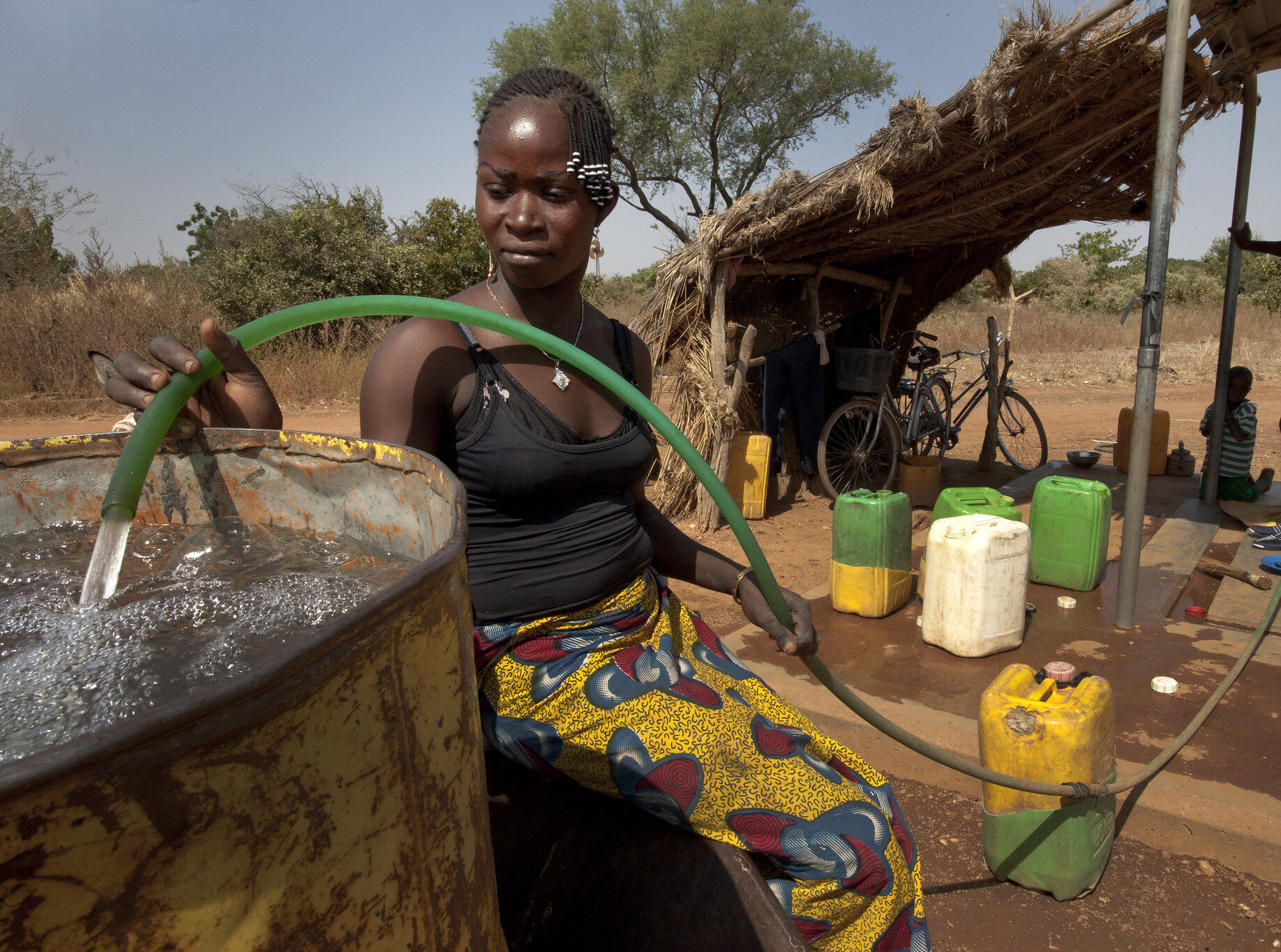 A woman filling a water container with a hose