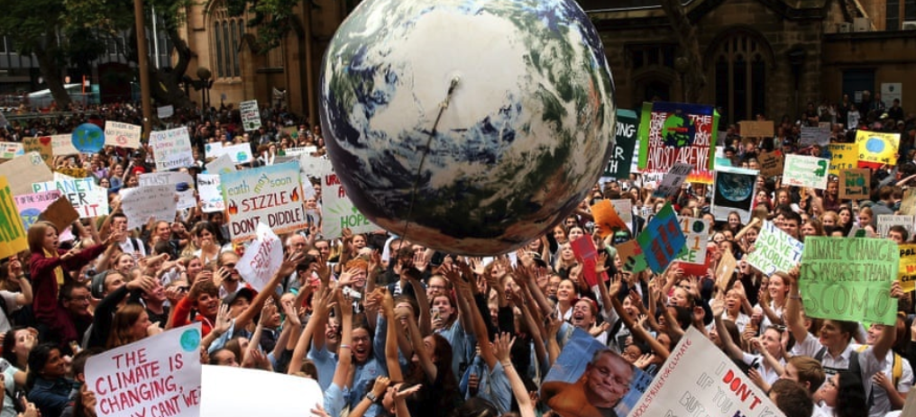 People gather with climate change signs and push a ballon with the shape of the earth into the earth